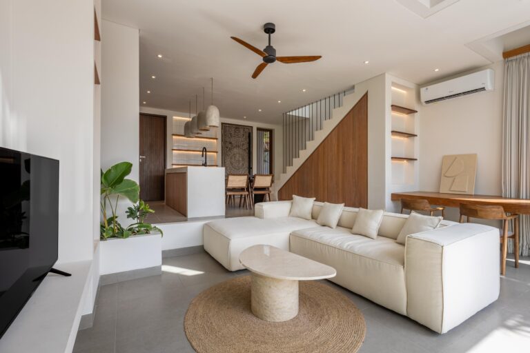 Modern living room with beige sofa and kitchen.