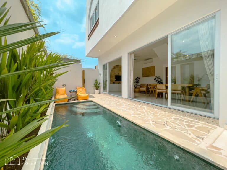 Modern villa courtyard with pool and patio seating.