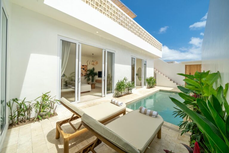 Luxurious villa with pool and lounge chairs.