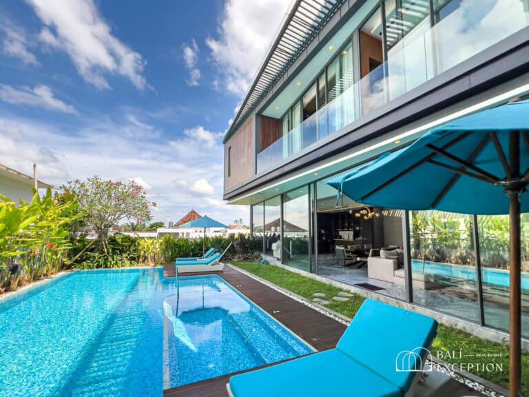 Modern villa with pool and lounge chairs.