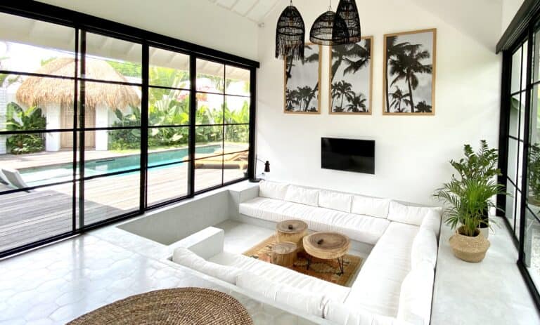 Modern living room with pool view and tropical decor.