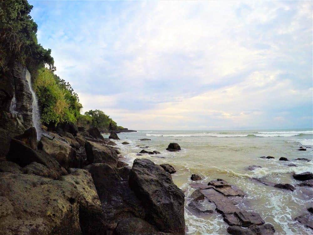 Rocky coastline with a waterfall and cloudy sky