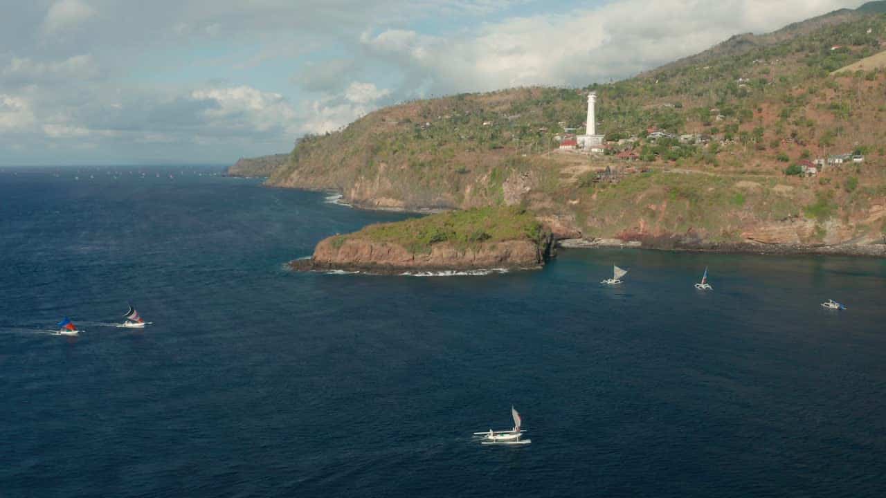 Coastal landscape with boats and a lighthouse.