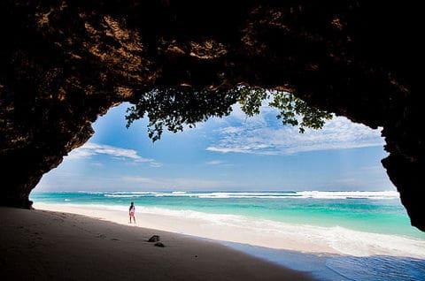 Person on beach viewed from cave opening