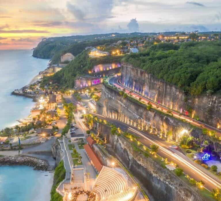 Scenic coastal road at sunset with colorful lights.