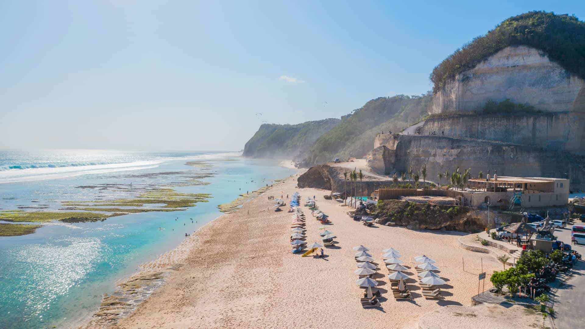 Sunny beach with cliffs and umbrellas