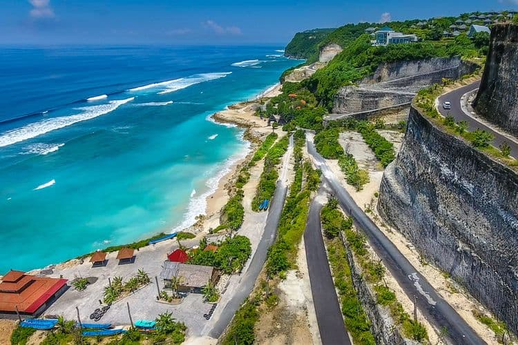 Coastal road by blue ocean waves and cliffs