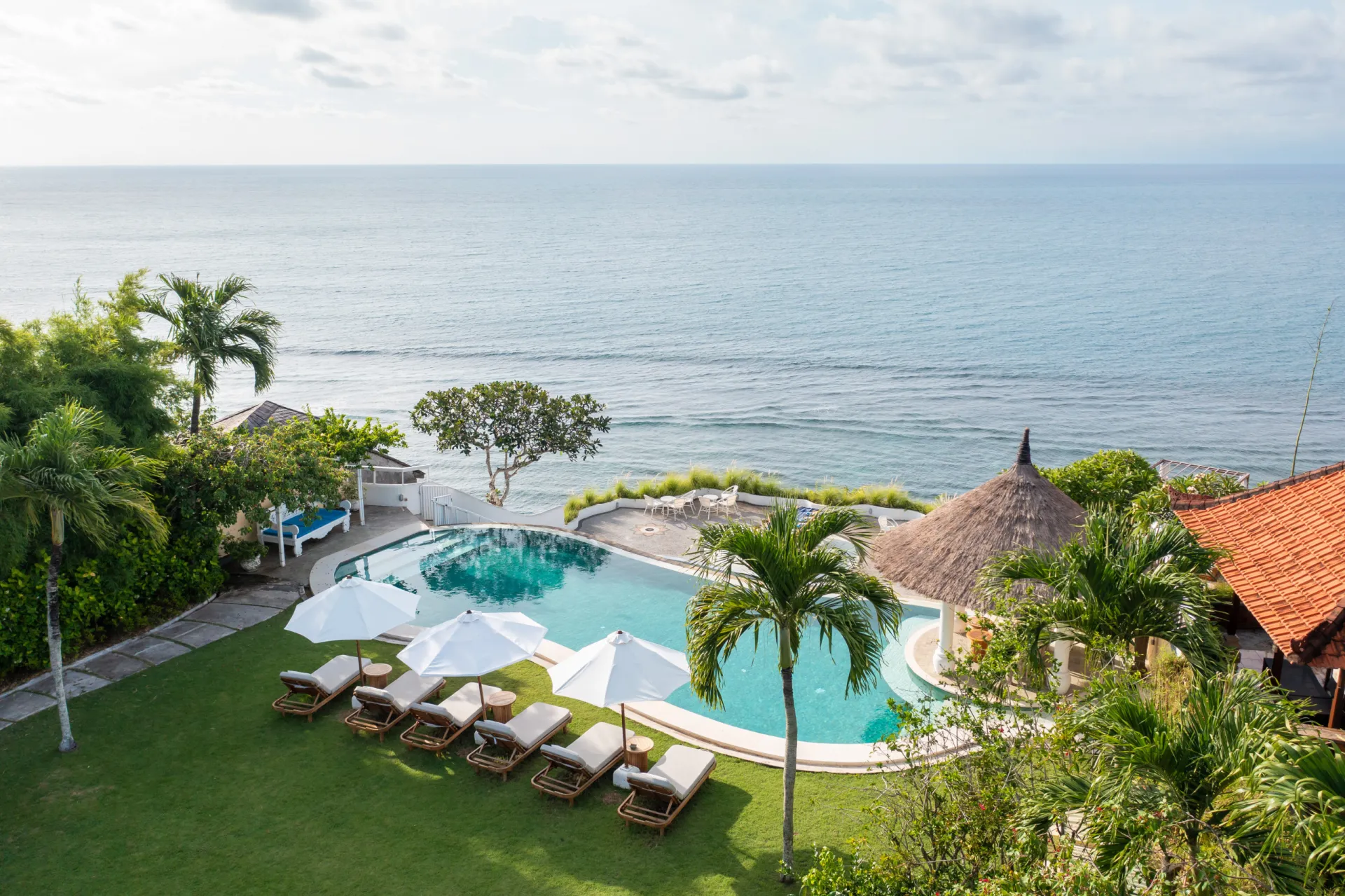 Oceanfront pool with lounge chairs and umbrellas