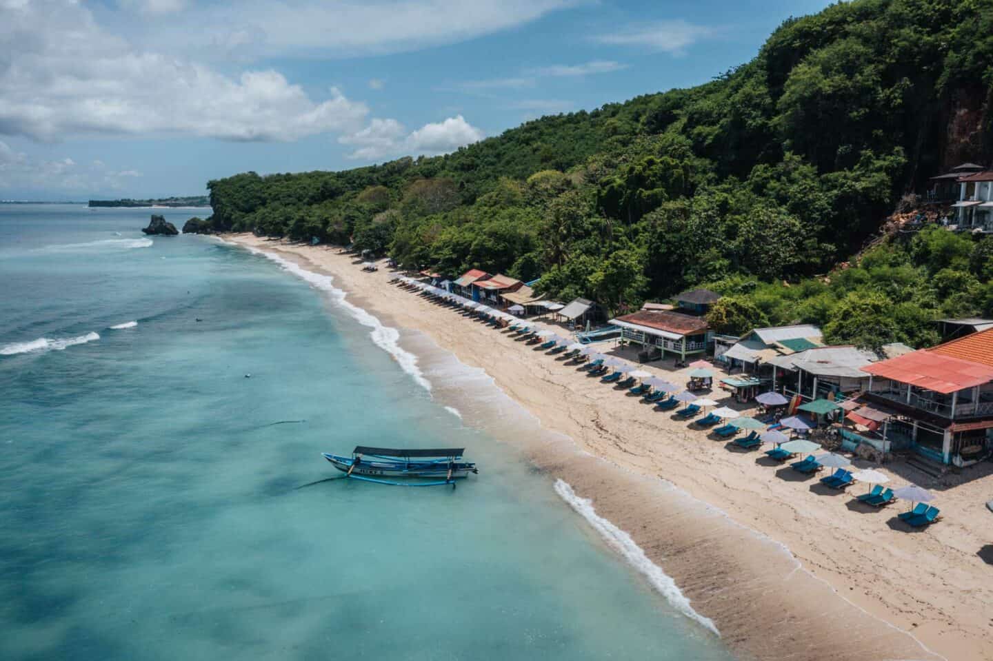 Tropical beach with huts and boat in ocean