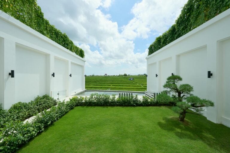 Lush garden with white walls and distant fields.