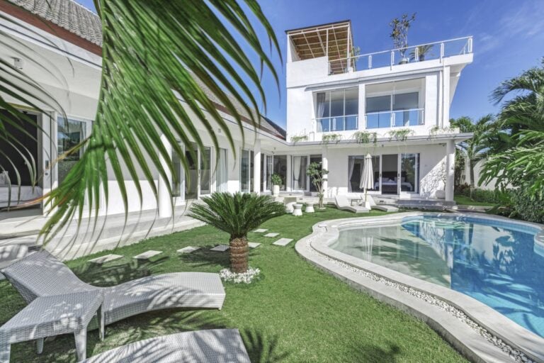 Modern white villa with pool and garden view.