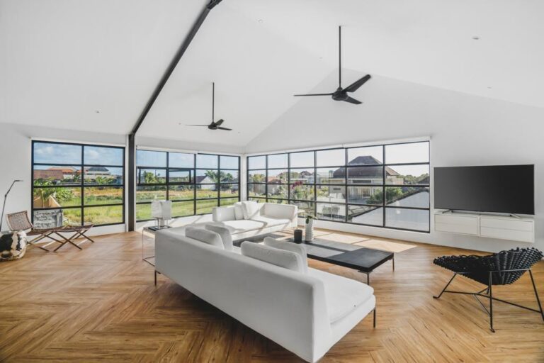 Modern living room with large windows and white sofas.