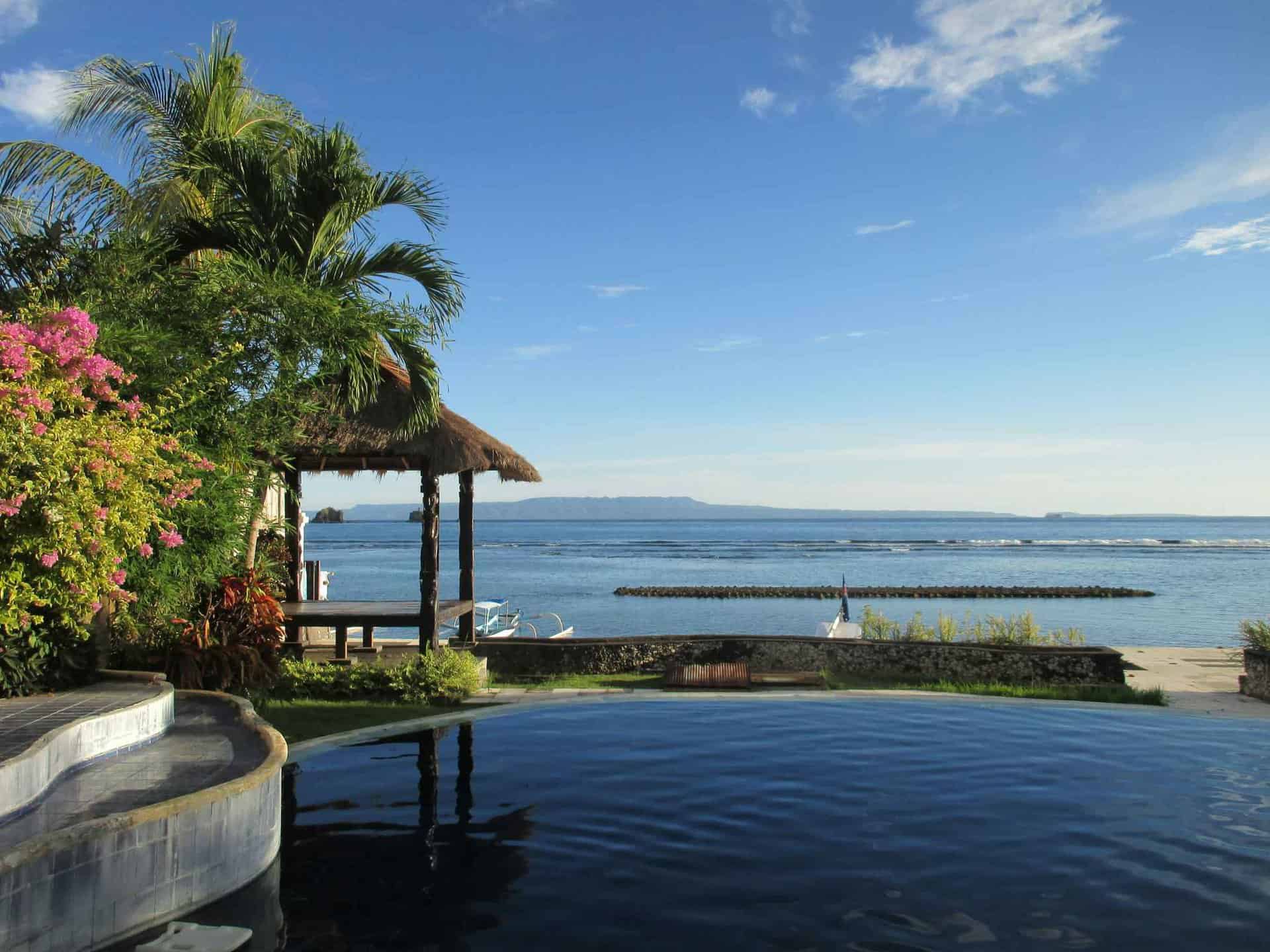 Tropical beach view with pool and gazebo.