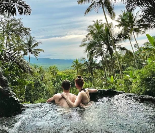 Couple relaxing in jungle infinity pool