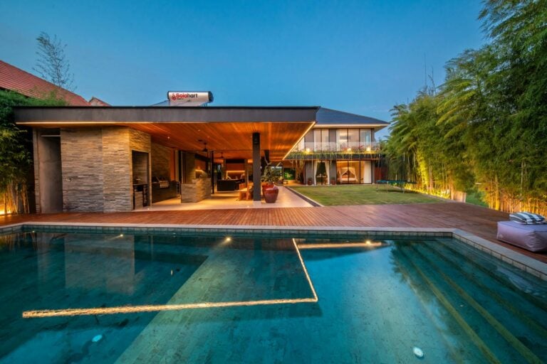 Modern house with pool and garden at sunset.