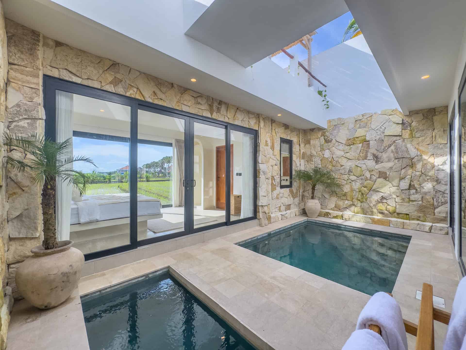 Modern villa courtyard with pool and stone walls.