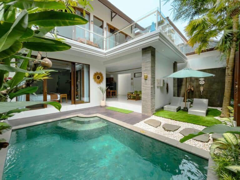 Modern villa courtyard with pool and lounge chairs.