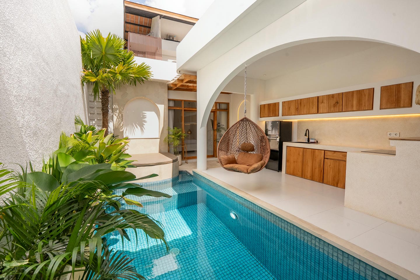 Modern villa with pool, plants, and hanging chair.