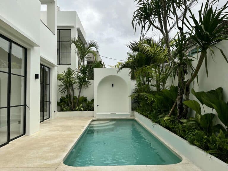 Modern white villa with small pool and palm trees.