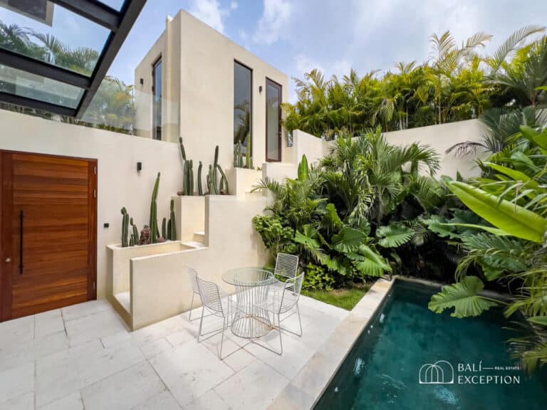 Modern villa courtyard with pool and lush greenery.