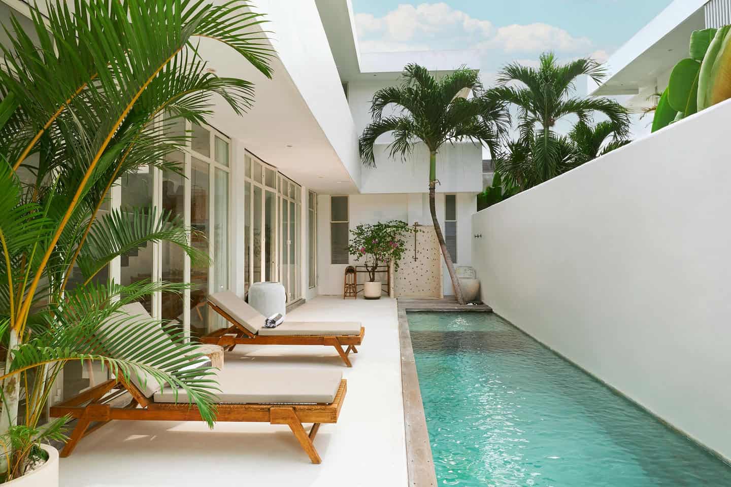 Modern villa courtyard with pool and loungers.