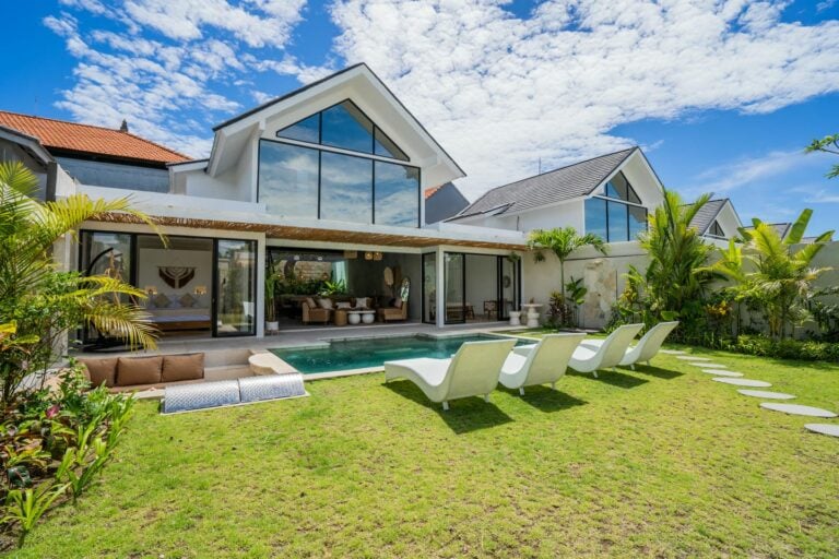 Modern villa with pool and lounge chairs.