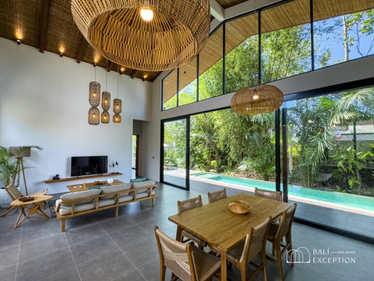 Spacious tropical living room with large windows and pool.