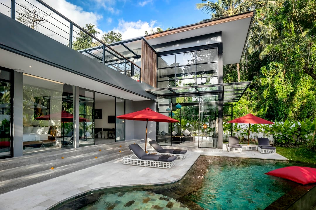 Modern villa with pool and red umbrellas.