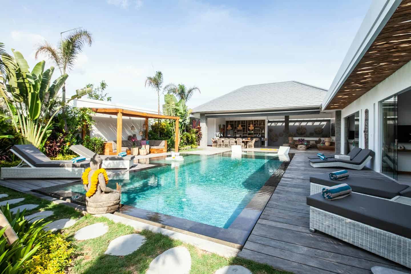 Luxurious pool surrounded by tropical garden and lounge chairs.