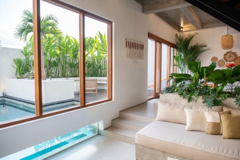 Modern indoor-outdoor living space with pool and plants.