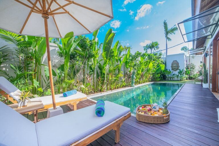 Tropical poolside with loungers and fruit basket.