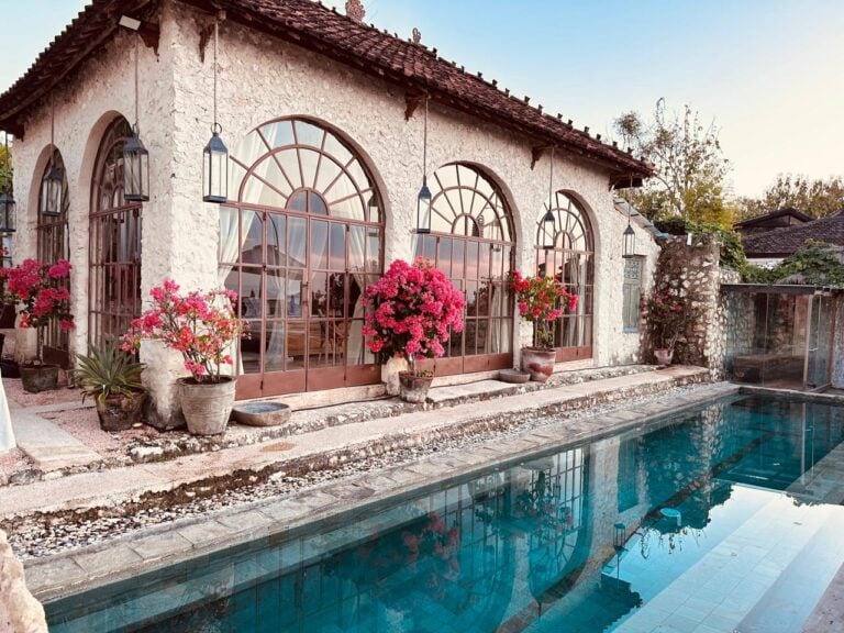 Rustic stone house with pool and flowers.