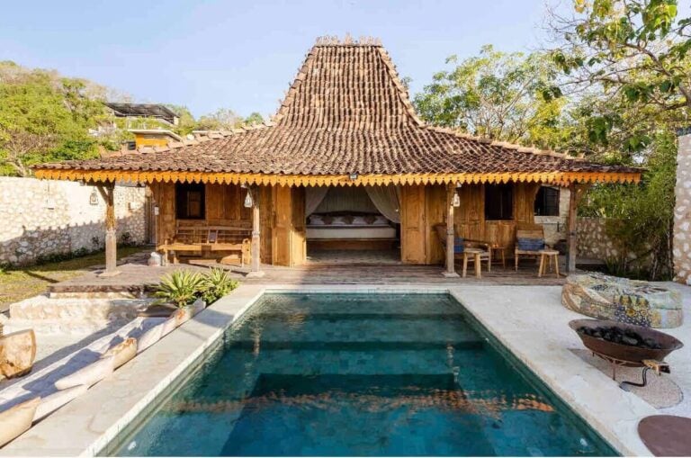 Rustic wooden house with swimming pool in tropical setting.
