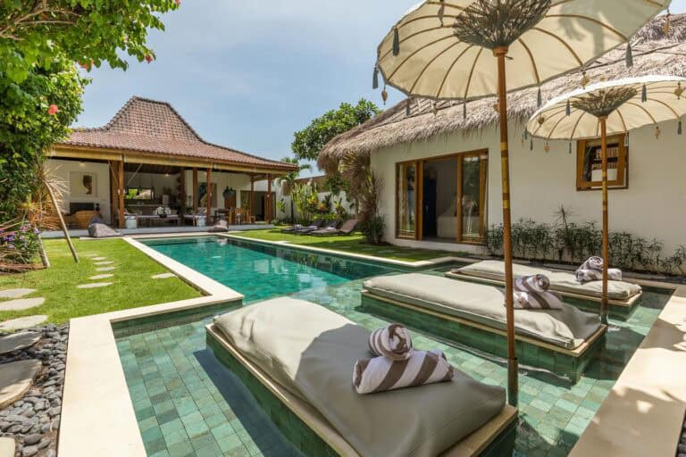 Luxury villa with pool and loungers in tropical setting.