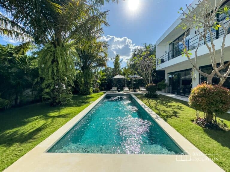 Luxury villa with pool and palm trees in sunlight.