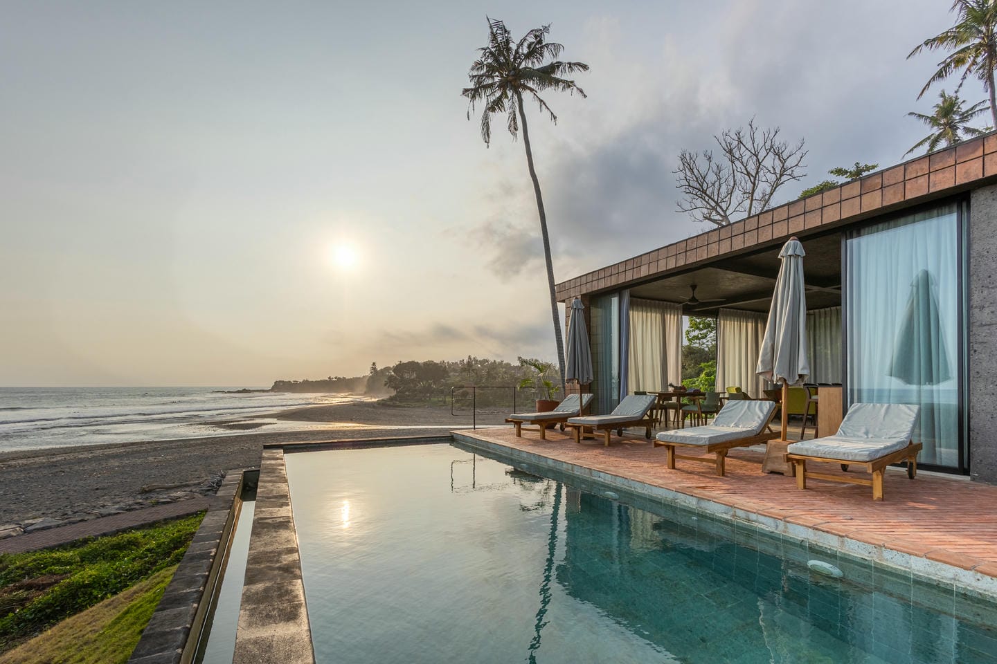 Beachfront villa with pool at sunset view.