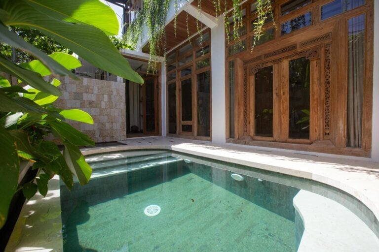 Tropical patio with small pool and wooden windows.