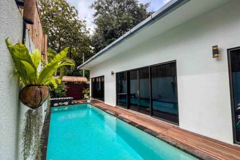 Modern poolside villa with tropical plants.