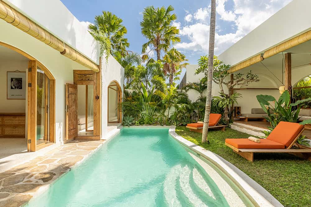 Tropical villa with pool and sun loungers.
