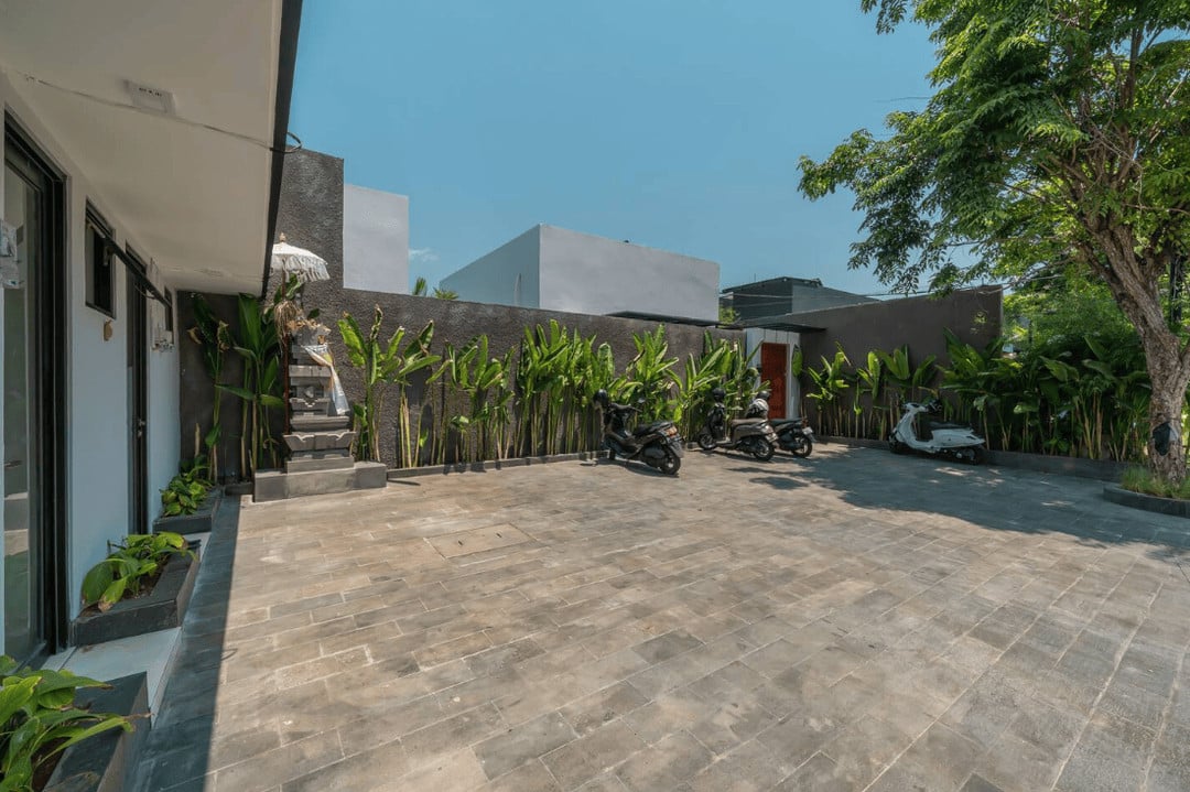 Spacious courtyard with scooters parked and greenery.