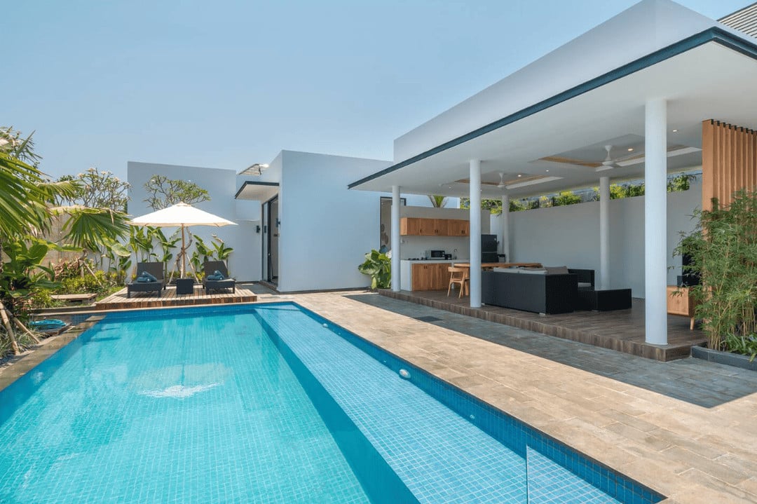 Modern outdoor patio with pool and lounge chairs.