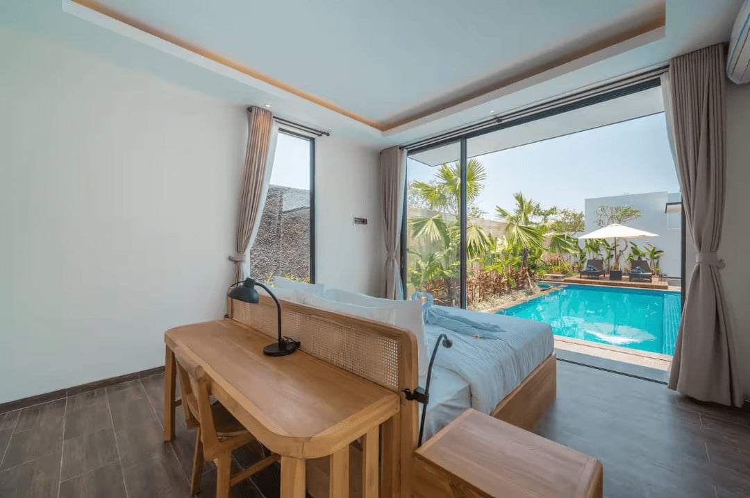 Bedroom with pool view through glass doors.